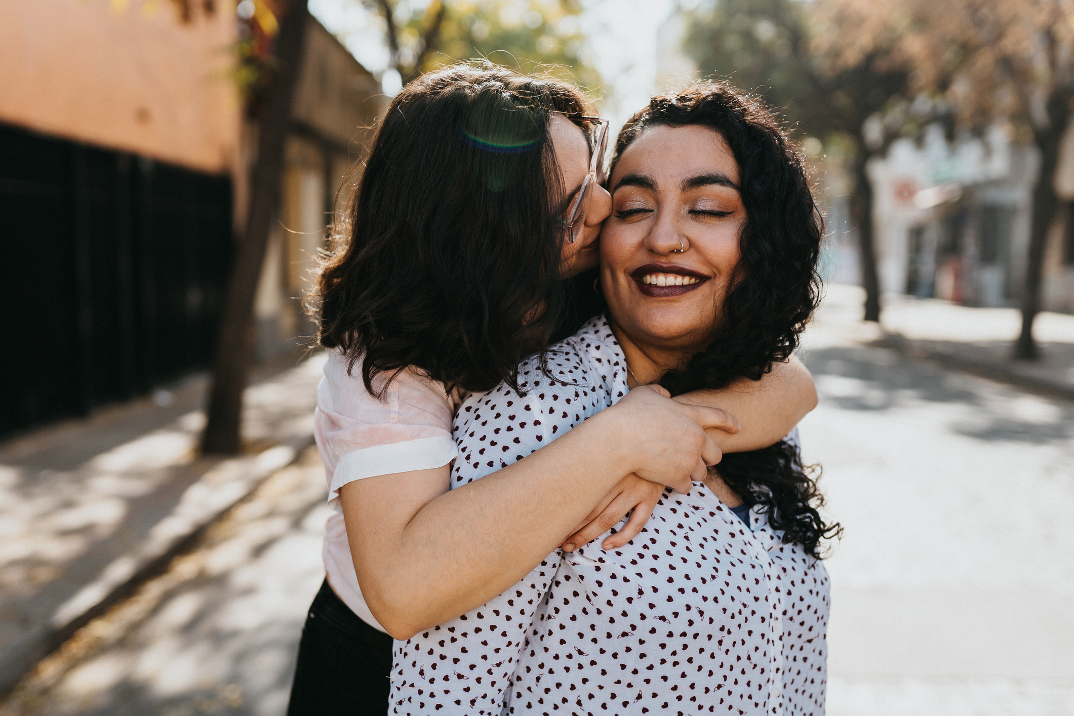 Young lesbian couple embracing outdoors in city Young lesbian couple embracing outdoors in city